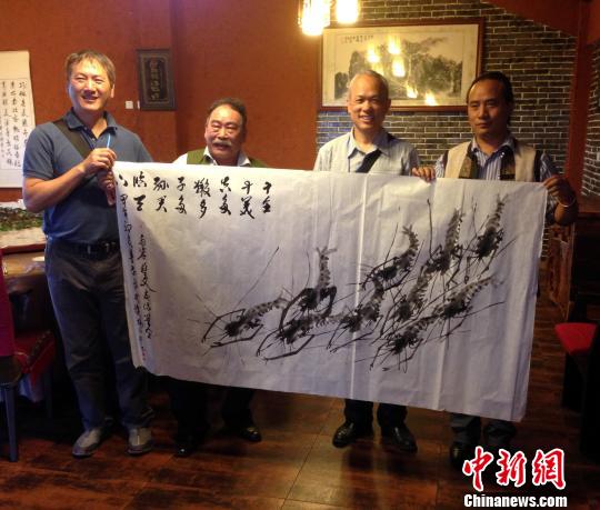 臺灣畫家楊信弘(左2)畫群蝦贈予云南當(dāng)?shù)厝耸? alt=