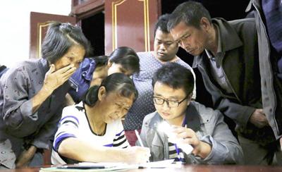 廣西融安縣大坡鄉(xiāng)崗偉村第一書記陳中偉打亮手機,給村民講解貧困戶入戶評估表。