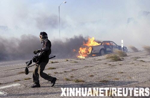 10月21日,一名新聞?dòng)浾咴诿绹?guó)加利福尼亞州馬利布地區(qū)山林大火現(xiàn)場(chǎng)走過燃燒的小汽車。當(dāng)天,距離洛杉磯西南約30公里的馬利布地區(qū)發(fā)生山林大火,目前已造成至少500英畝的山林和數(shù)幢建筑物被毀,數(shù)百人被緊急疏散。 新華社/路透